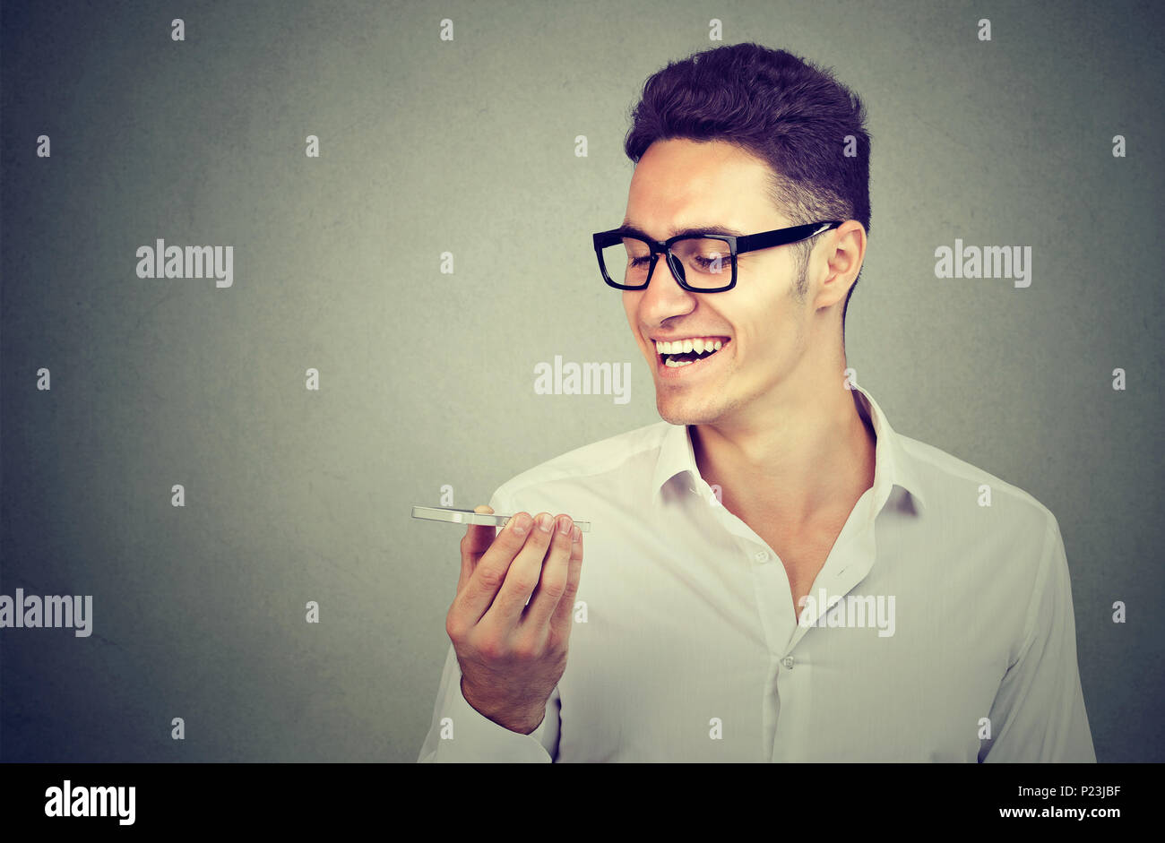Uomo che utilizza un telefono intelligente funzione riconoscimento vocale sulla linea isolata sul muro grigio sfondo Foto Stock