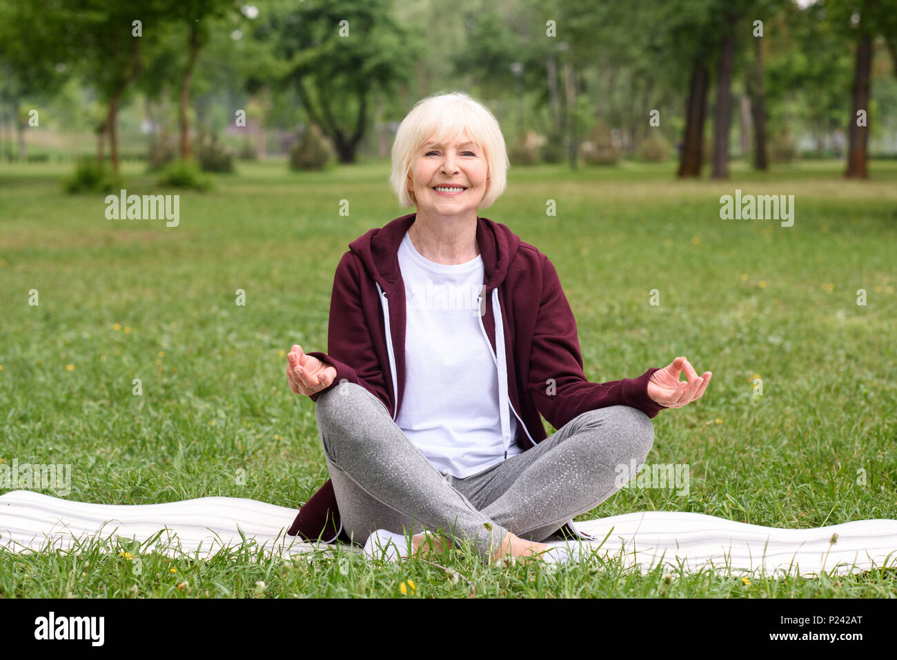 Felice senior donna meditando con gyan mudra sul materassino yoga in posizione di parcheggio Foto Stock