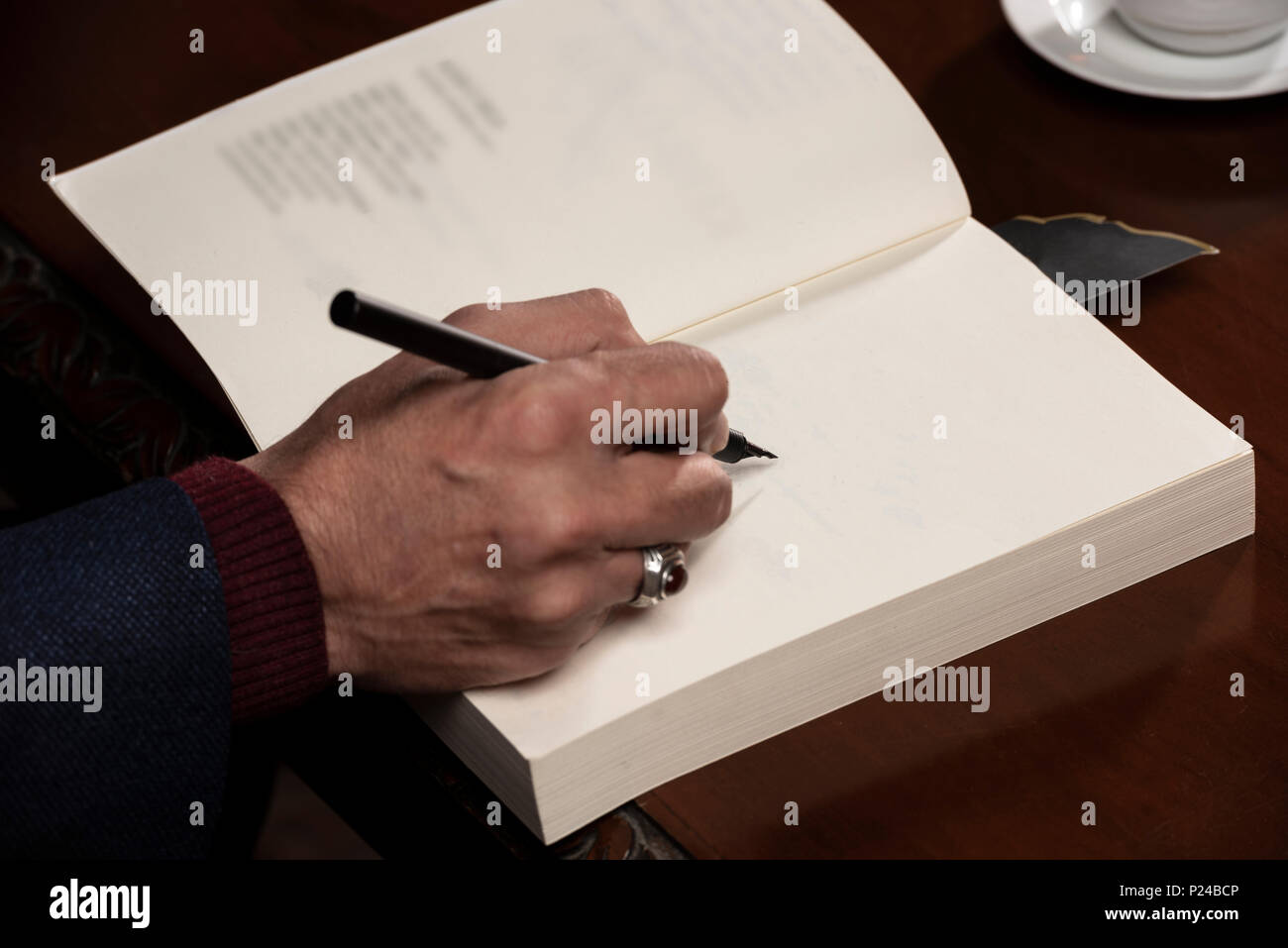 Man mano con penna che scrive sul libro. Foto Stock