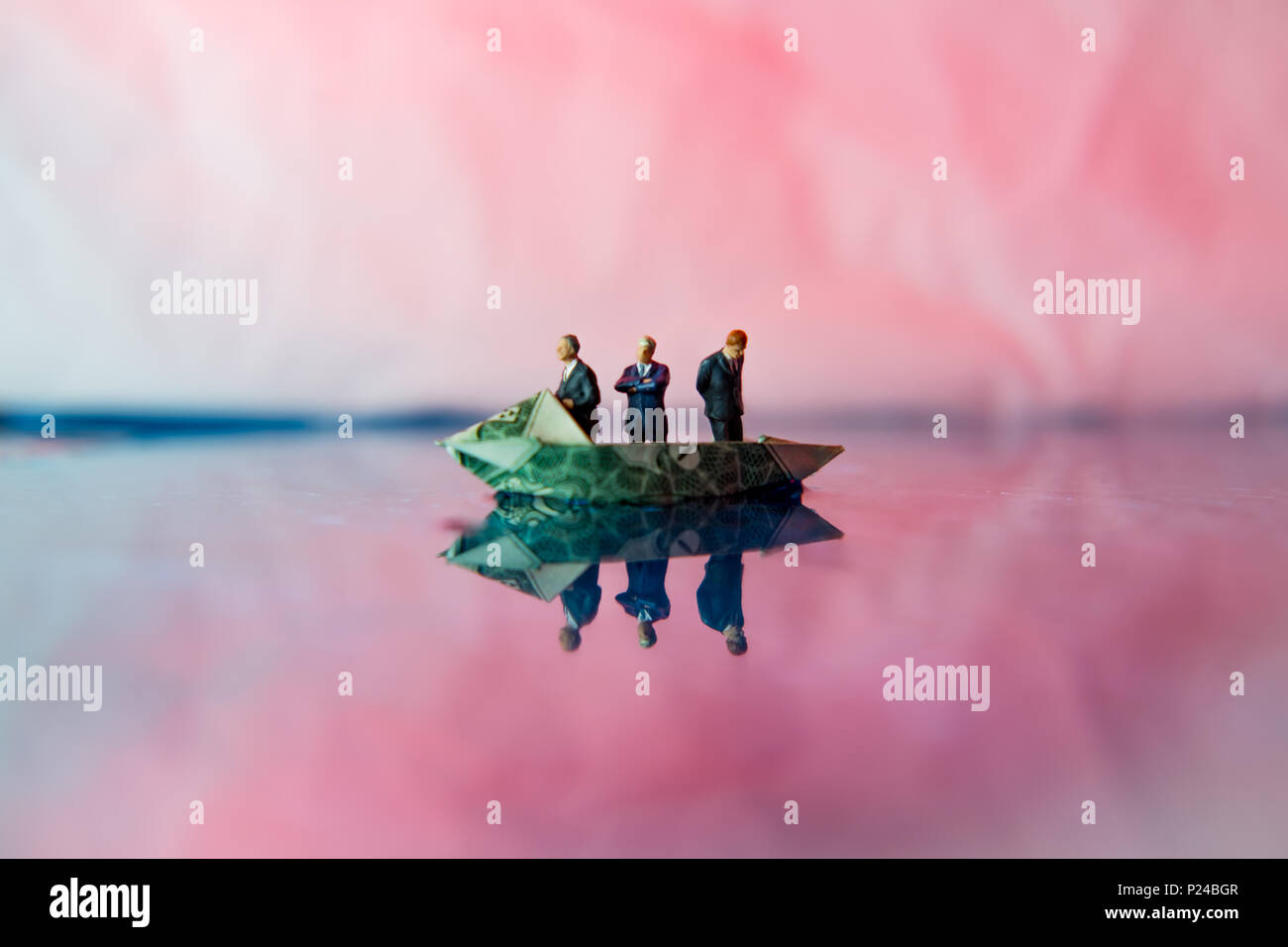 Miniatura imprenditori di figurine di giro sul dollaro origami yacht Foto Stock