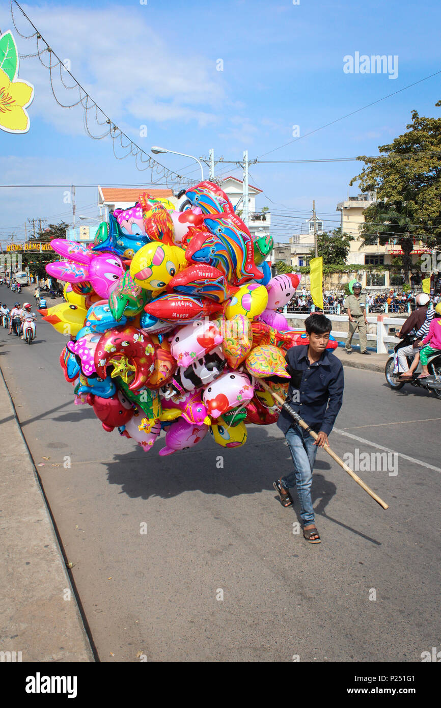 Phan Thiet , il Vietnam - Gennaio 2014: Giovani vietnmese uomo vendita di palloncini colorati su strada durante il nuovo anno in Phan Thiet , il Vietnam Foto Stock