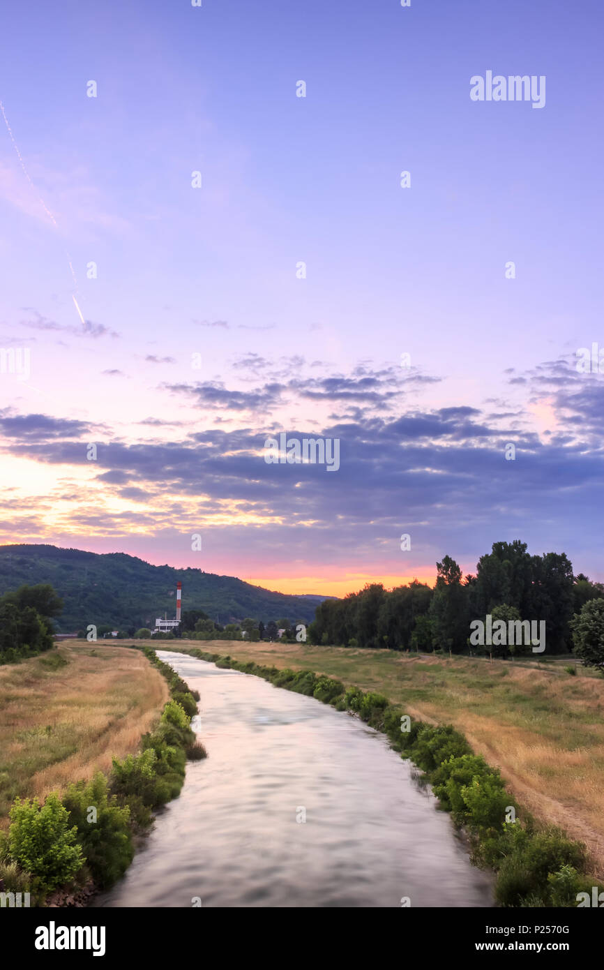 Vista verticale del moto sfocata Nisava fiume di Pirot e distante il vecchio stabilimento durante la vivace, burning sunset Foto Stock