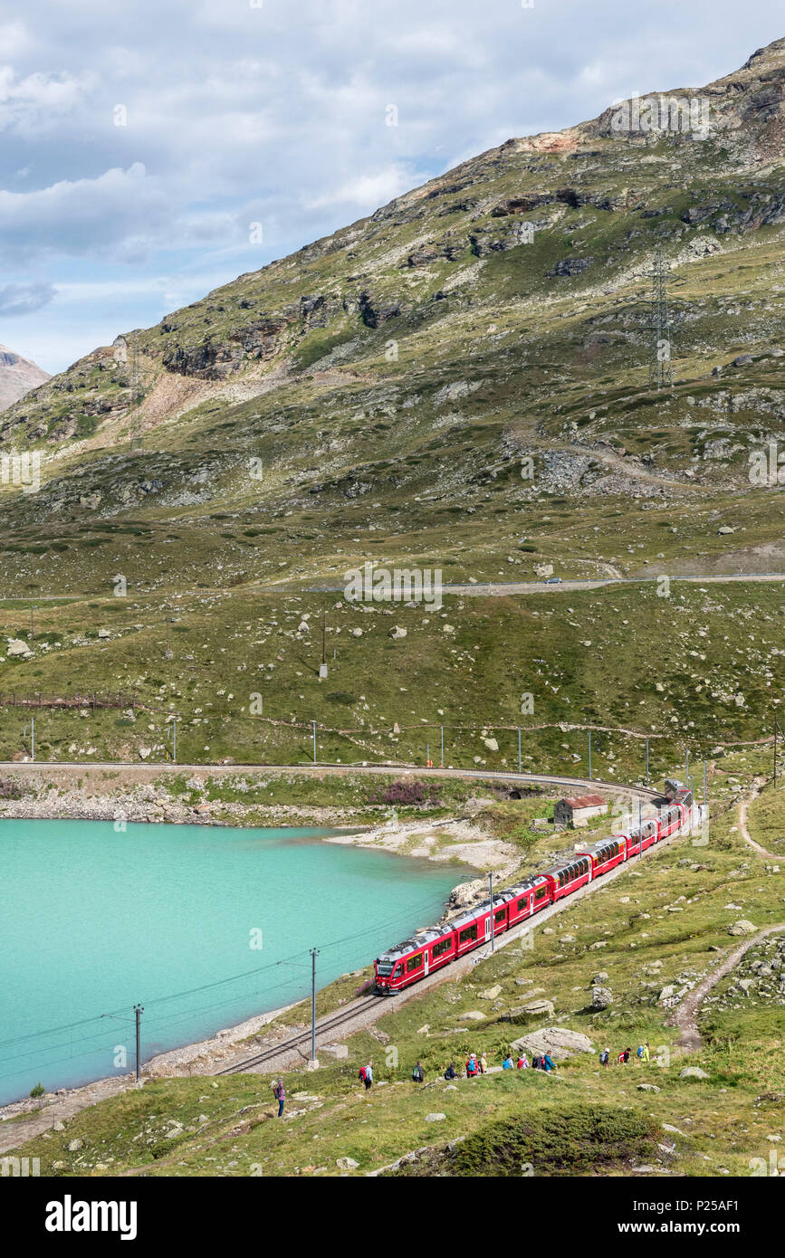Il Bernina Express e gli escursionisti passa lungo il Lago Bianco in un giorno di estate, Passo Bernina del Cantone dei Grigioni, Engadina, Svizzera, Europa Foto Stock