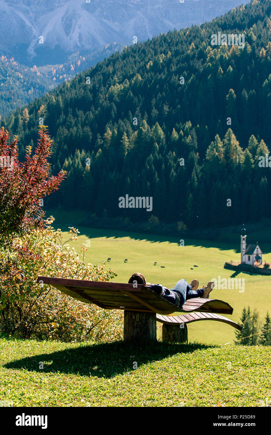 Ragazza rilassante su un banco delle Dolomiti italiane Alpi, Val di Funes, Trentino Alto Adige, Italia Foto Stock