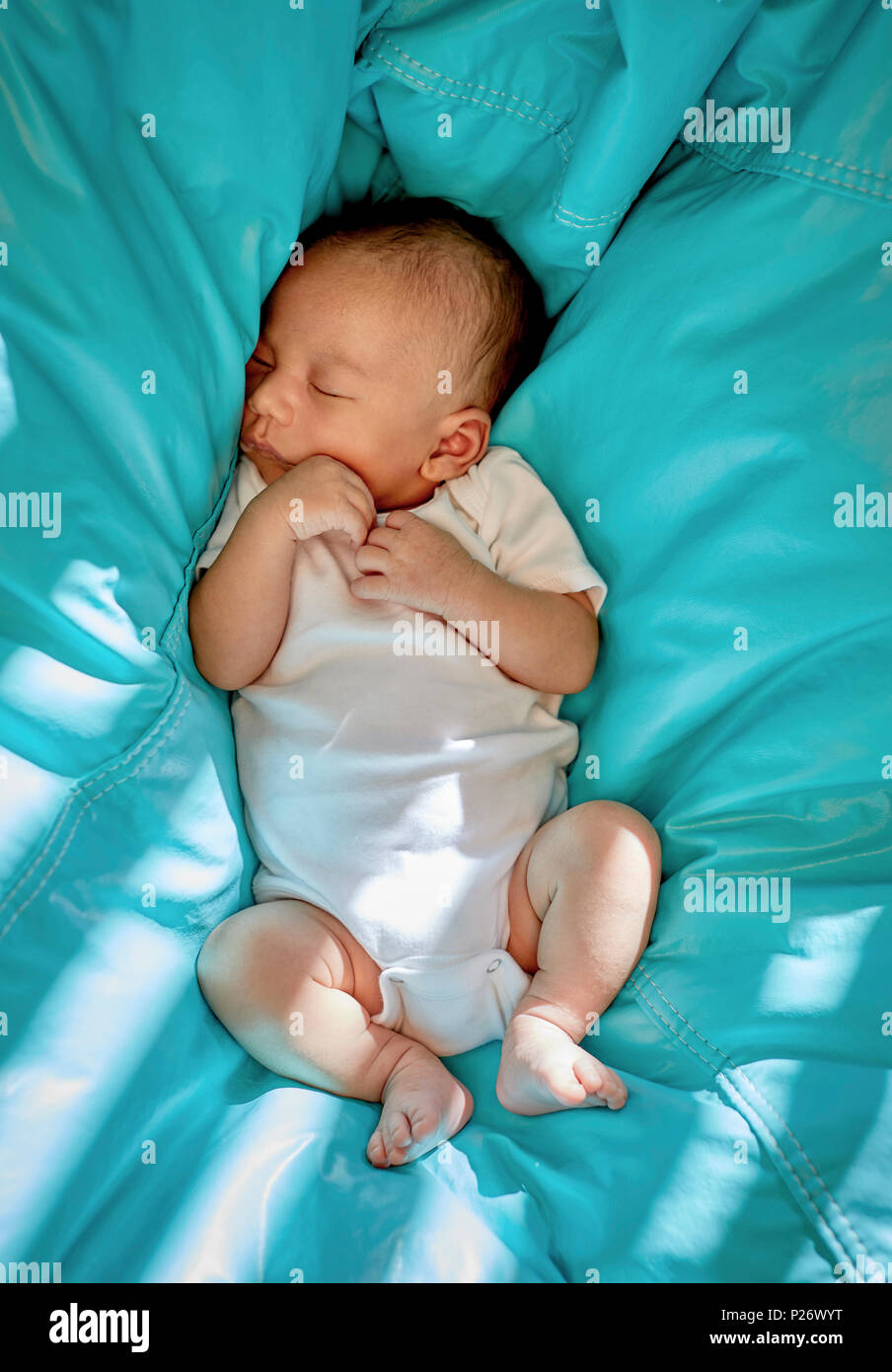 Bambino dorme in un sacchetto di fagioli con luce solare parziale Foto Stock