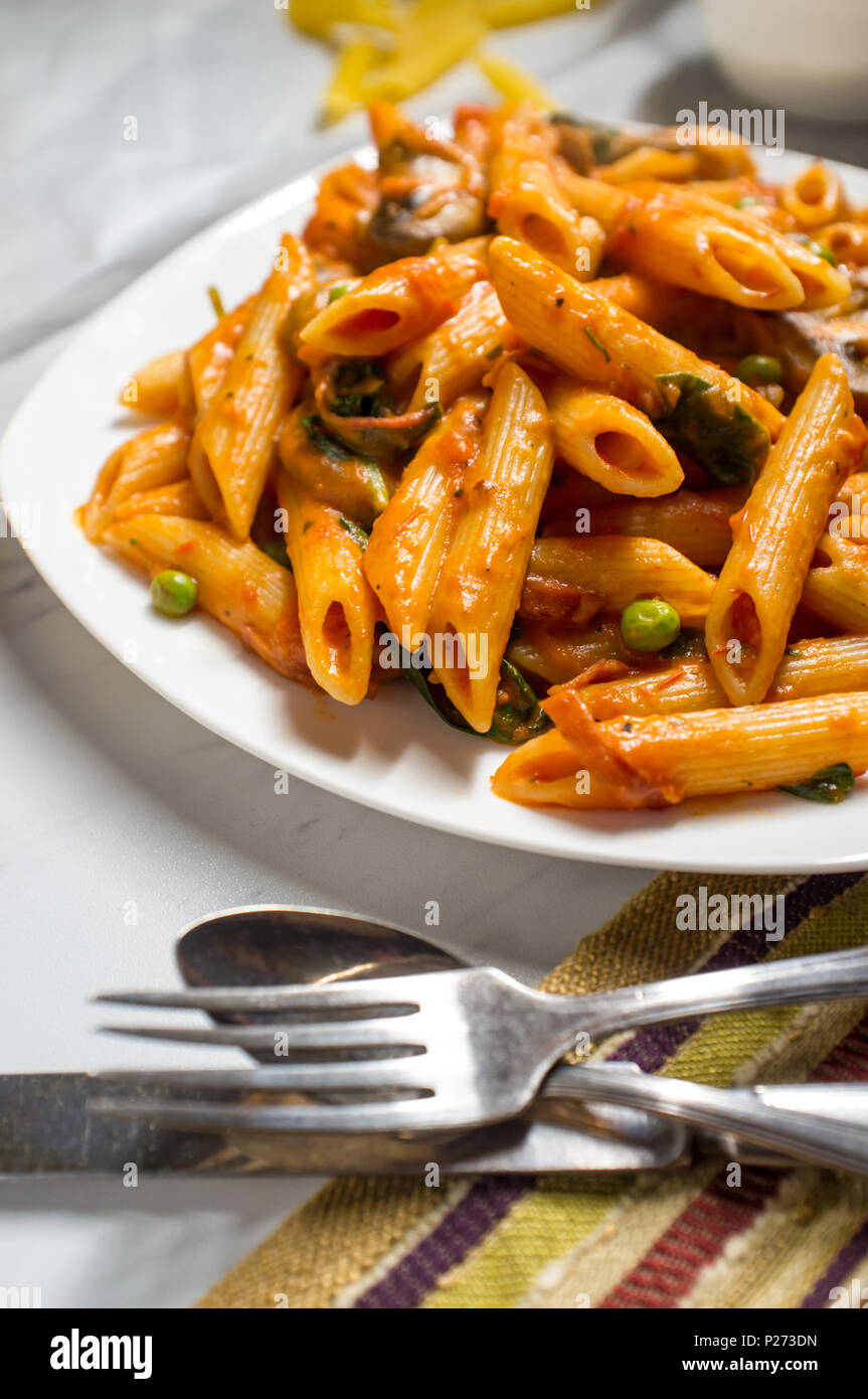 Penne Pasta In Vodka Cremosa Salsa Di Pomodoro Con Funghi Piselli E Spinaci Foto Stock Alamy