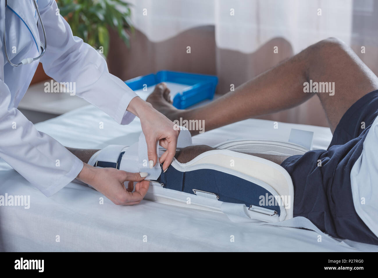 Immagine ritagliata di dottore mettendo sulla gamba del rinforzo per americano africano paziente Foto Stock