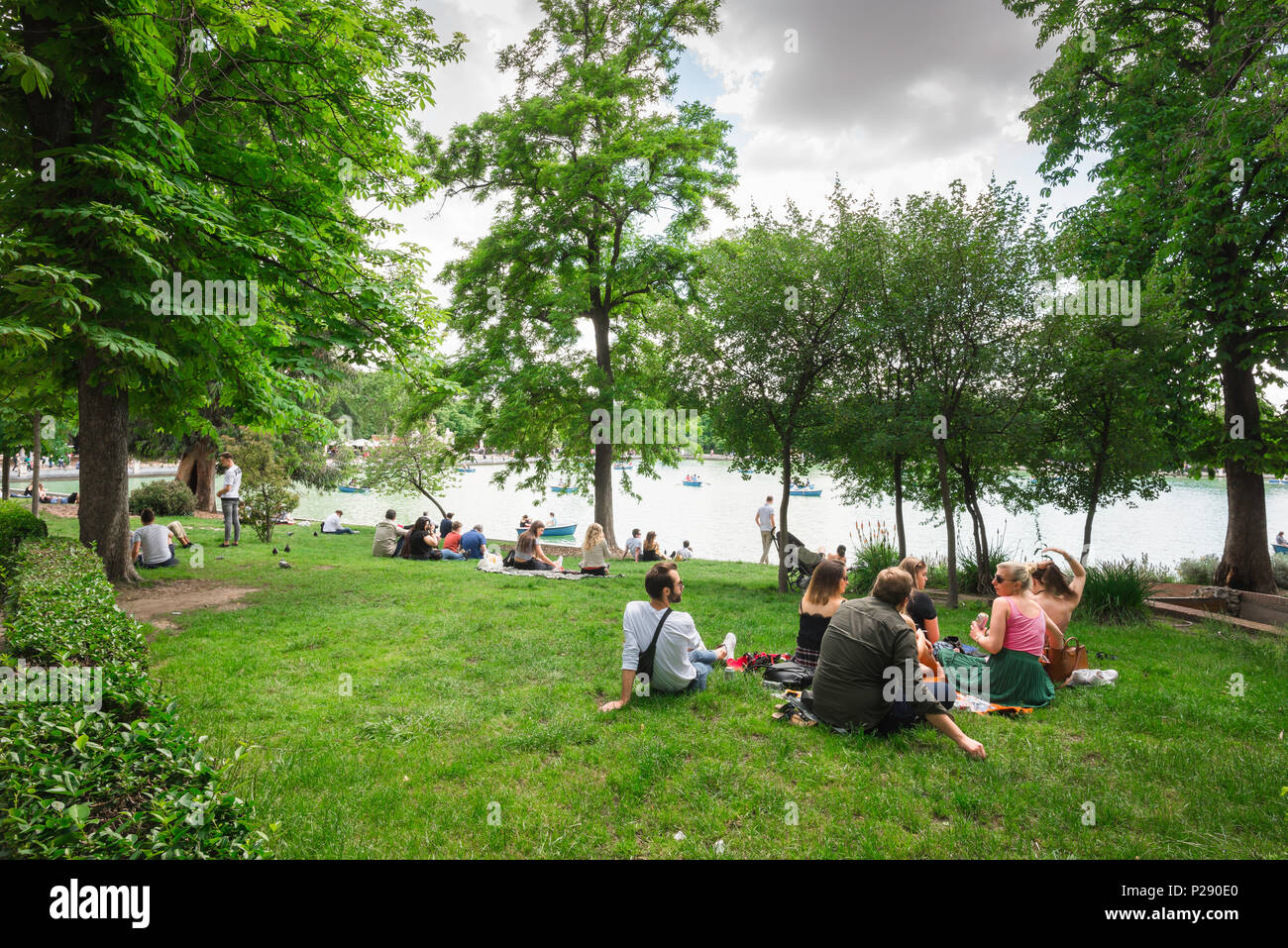 Parco del Retiro di Madrid, vista di un gruppo di giovani che condividono un pic-nic vicino al lago nel Parque del Retiro, nel centro di Madrid, Spagna. Foto Stock