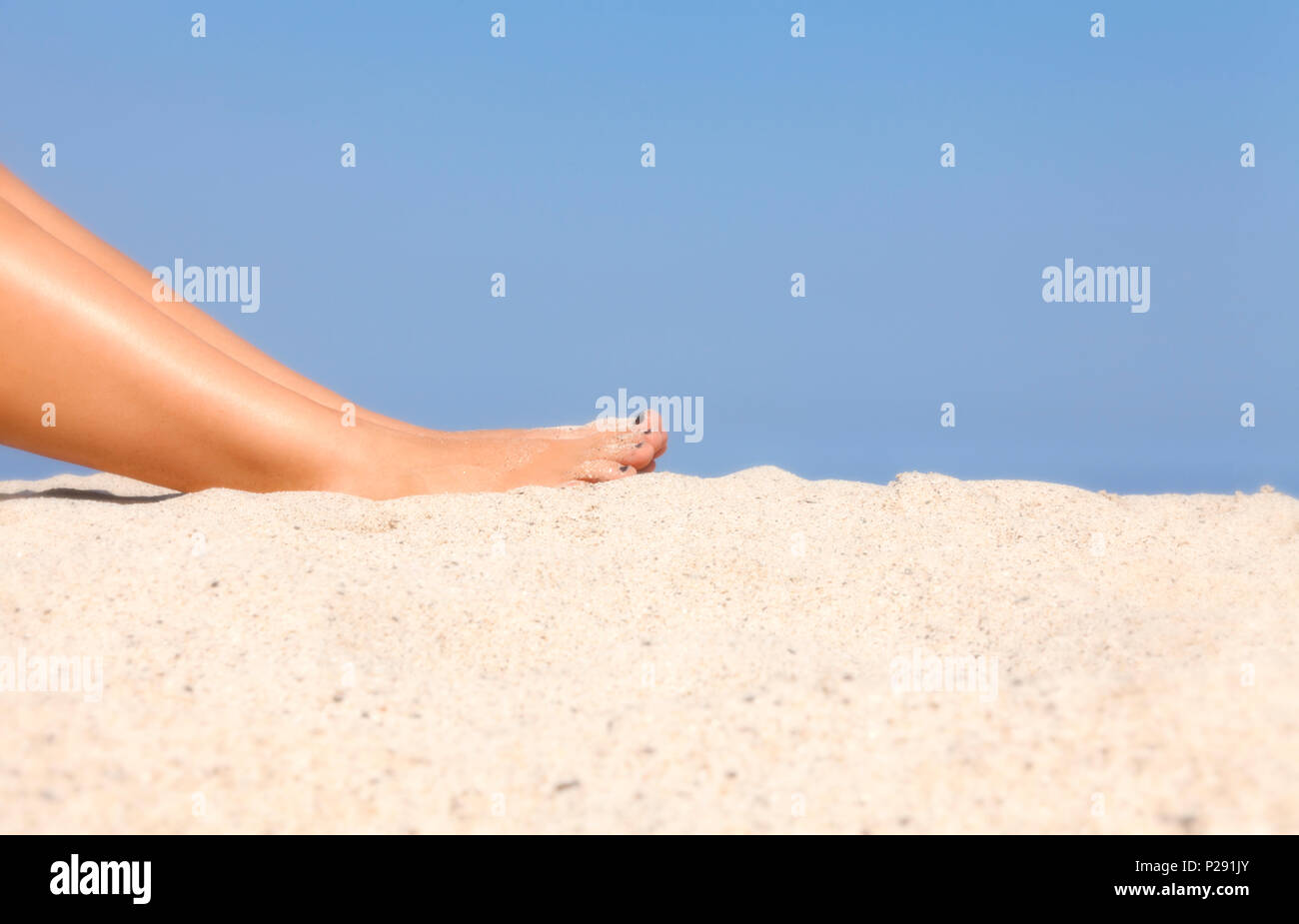 I piedi di una donna in spiaggia contro la sabbia. La vacanza estiva vacanza, libertà, rilassati. Foto Stock