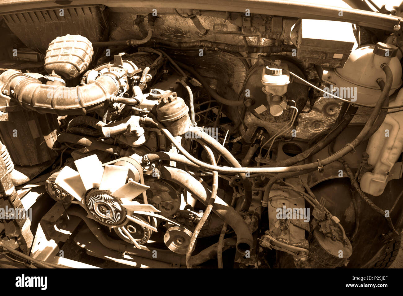 Vecchio rotto e sporco auto motore vicino, vista sotto il cofano in tonalità seppia Foto Stock