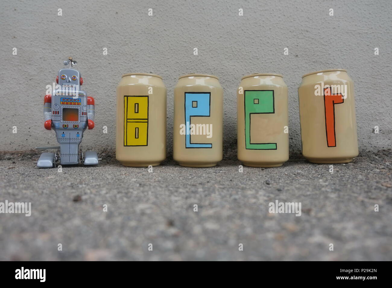 Testo della birra dipinto su lattine di birra con un robot giocattolo in lattina Foto Stock