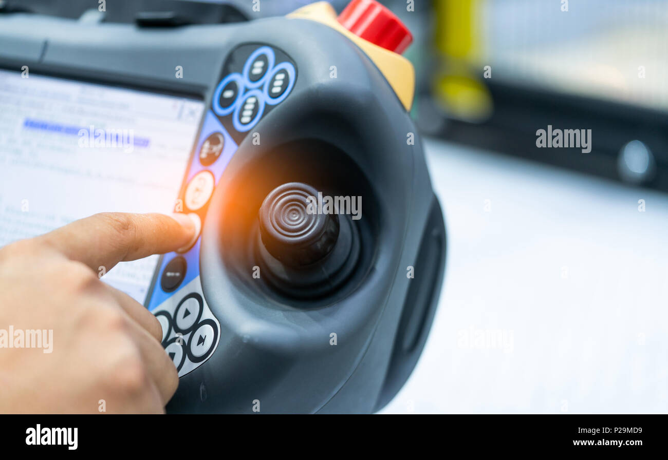 Ingegnere punto a mano in corrispondenza del joystick del robot di controllo in fabbrica. Utilizzare robot intelligenti nel settore manifatturiero per l industria 4.0 e concetto tecnologico. Foto Stock