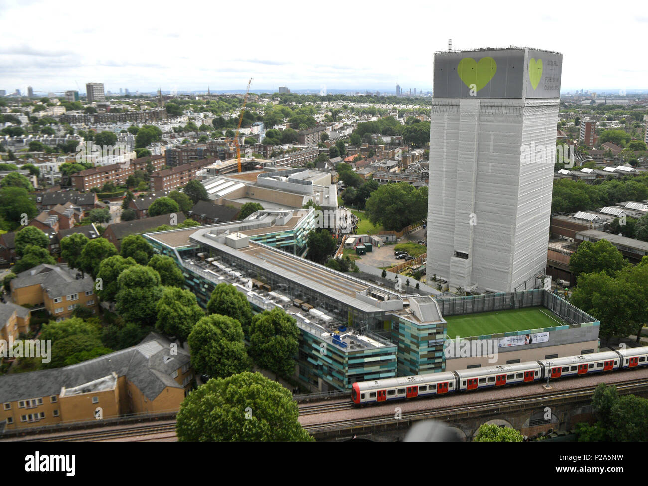 Un banner con un cuore verde è avvolto intorno alla torre Grenfell un anno su quanto blaze, quale rivendicato 72 vive. Foto Stock