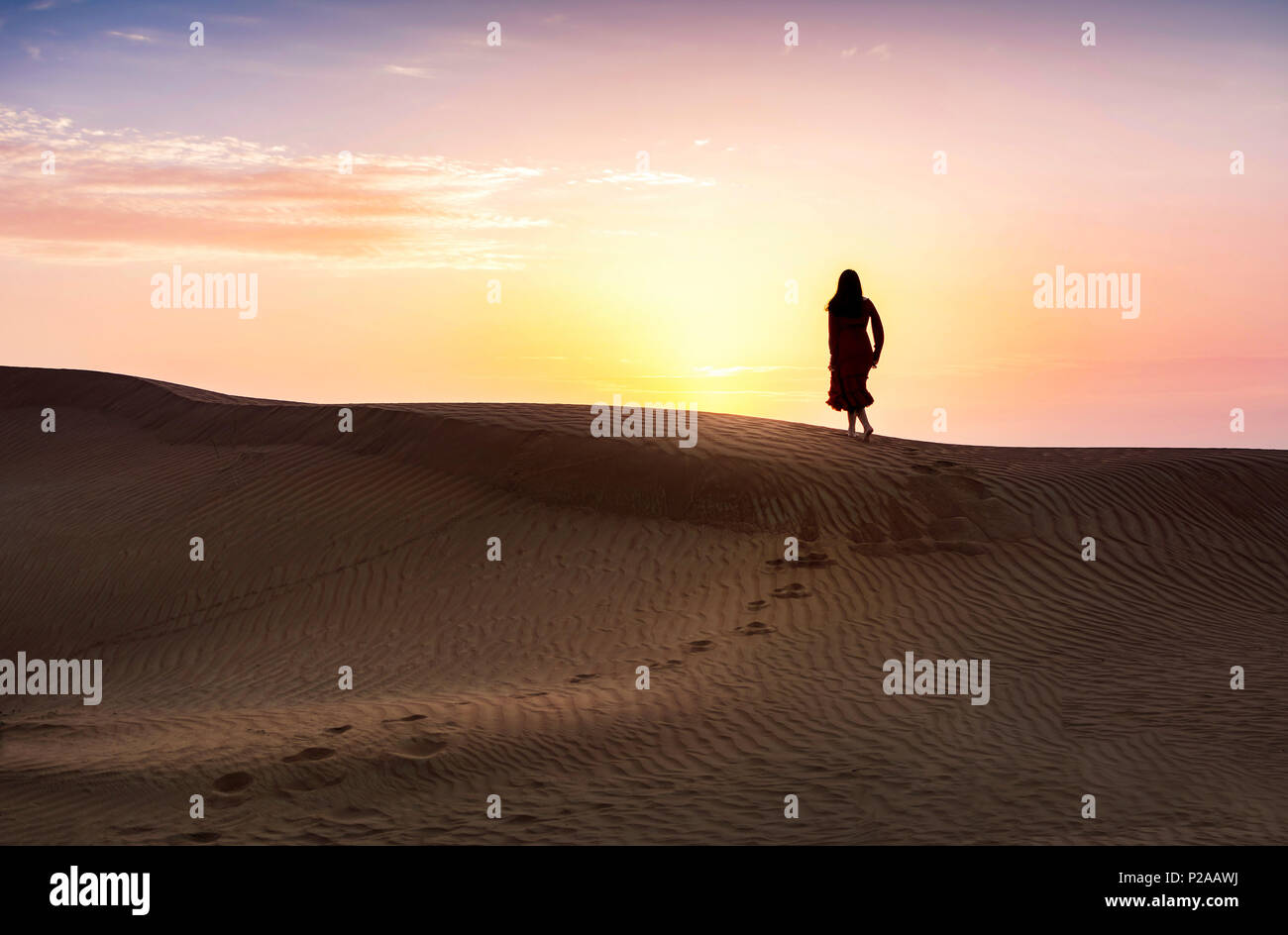 Donna che cammina nel deserto con vista tramonto Foto Stock