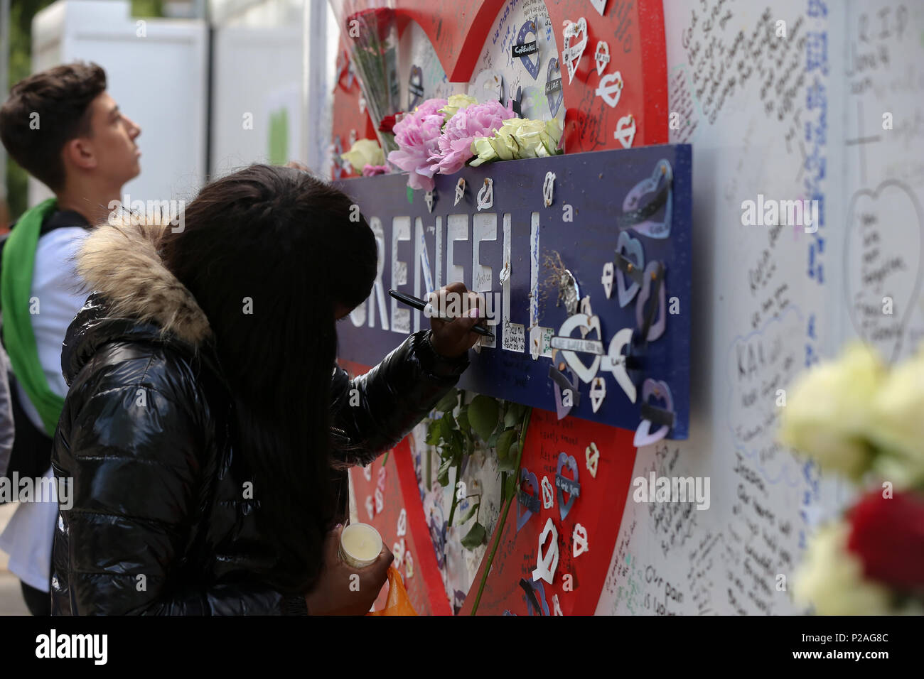 A ovest di Londra. Londra. Regno Unito 14 Giugno 2018 - Membri della famiglia lay ghirlande di fiori e la accensione di candele alla base della torre Grenfell fuori Kensington il centro per il tempo libero. L incendio è scoppiato il 14 giugno 2017 in 24 piani di Grenfell a torre dell'edilizia pubblica appartamenti nel Nord di Kensington, West London, in cui 72 persone hanno perso la loro vita. Credito: Dinendra Haria/Alamy Live News Foto Stock