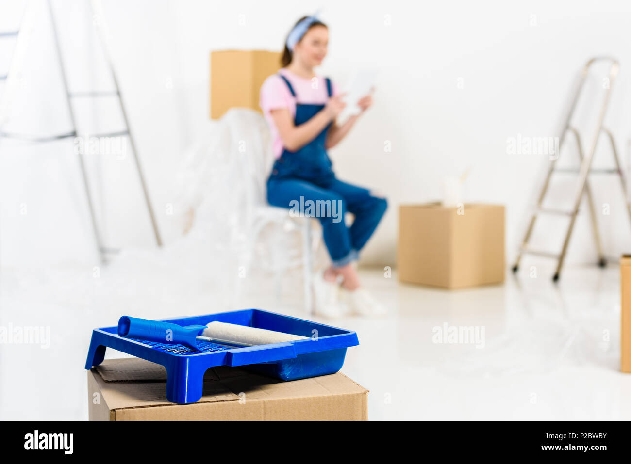 Ragazza seduta con pranzo caselle nella nuova casa con vassoio di vernice sul primo piano Foto Stock