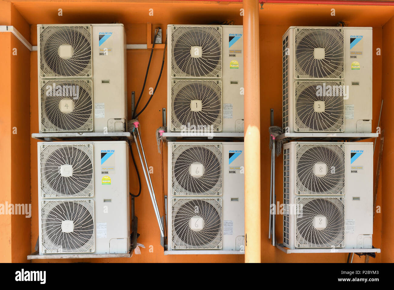 Una pila di condizionatore di aria condensatori di pilotaggio esterno più condizionatori d'aria in ambienti chiusi in una giornata calda. Foto Stock