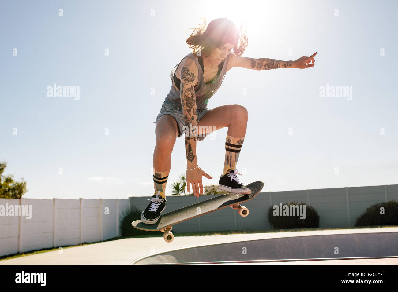 Skater femmina praticare lo skateboard a skate park. Le donne facendo ollie su skateboard. Foto Stock