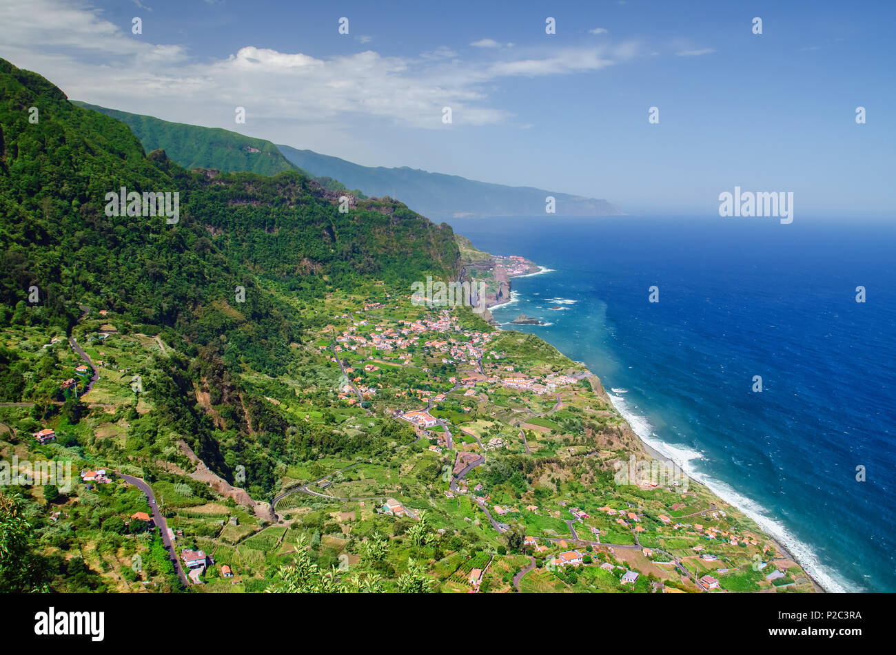 Splendida vista dal di sopra alla costa nord dell'isola di Madeira e profondo blu oceano Atlantico. Santana la città con la sua periferia sono circondata da alte montagne Foto Stock