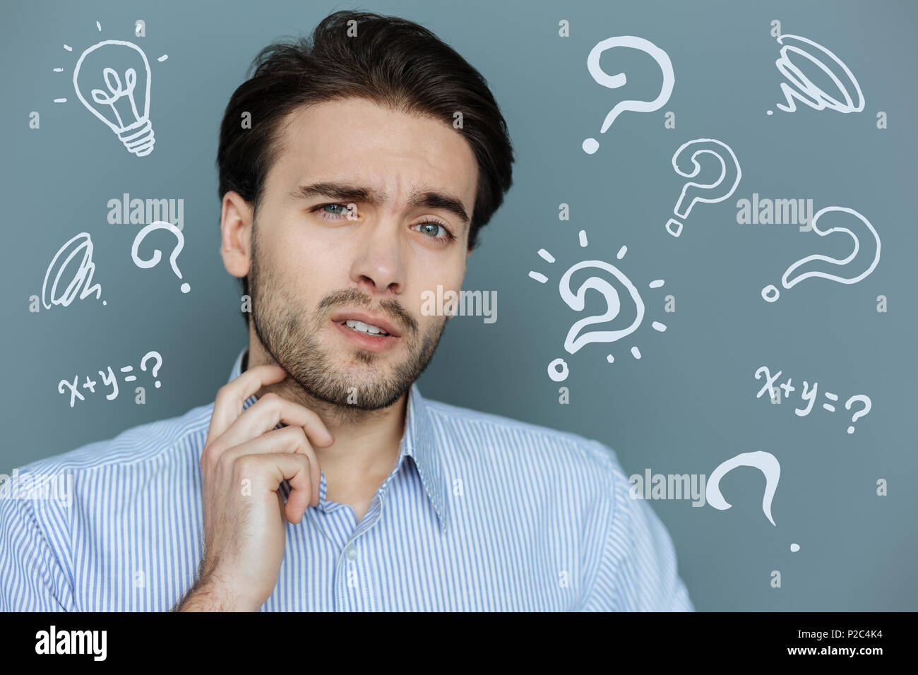Accigliata studente di graffiare la sua barba e guardando pensieroso Foto Stock