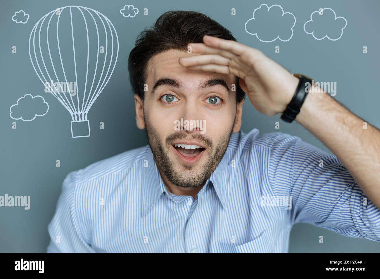 Eccitato giovane uomo sorridente e guardare i palloni ad aria calda battenti Foto Stock