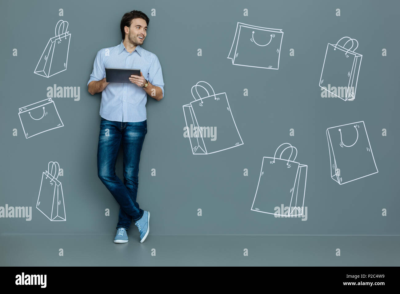 Felice l'uomo con una pastiglia di sorridere mentre si fanno acquisti online Foto Stock