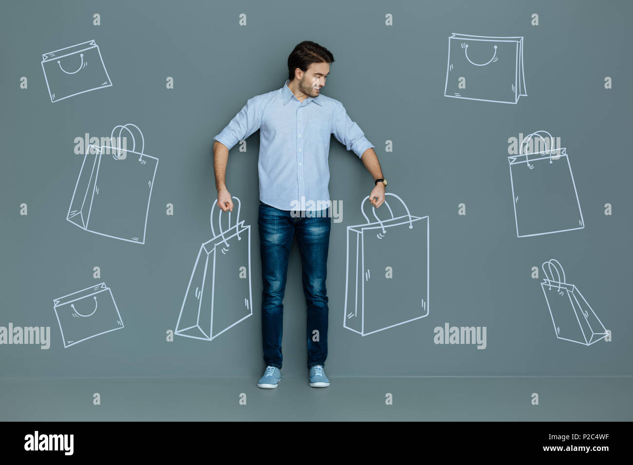 Uomo bello con le pesanti valigie dopo lo shopping Foto Stock