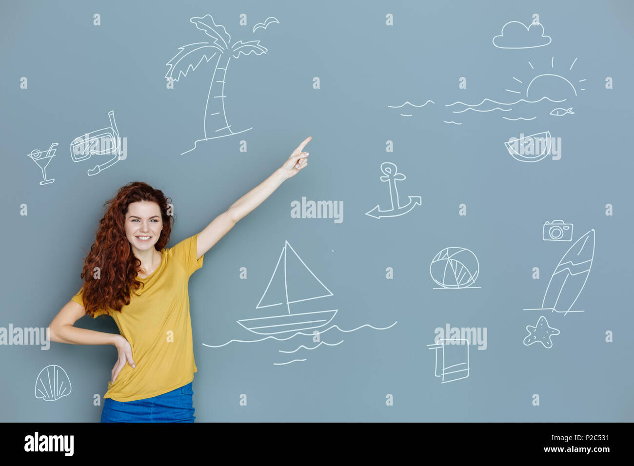Felice studente puntando il dito in alto e in attesa per il viaggio Foto Stock