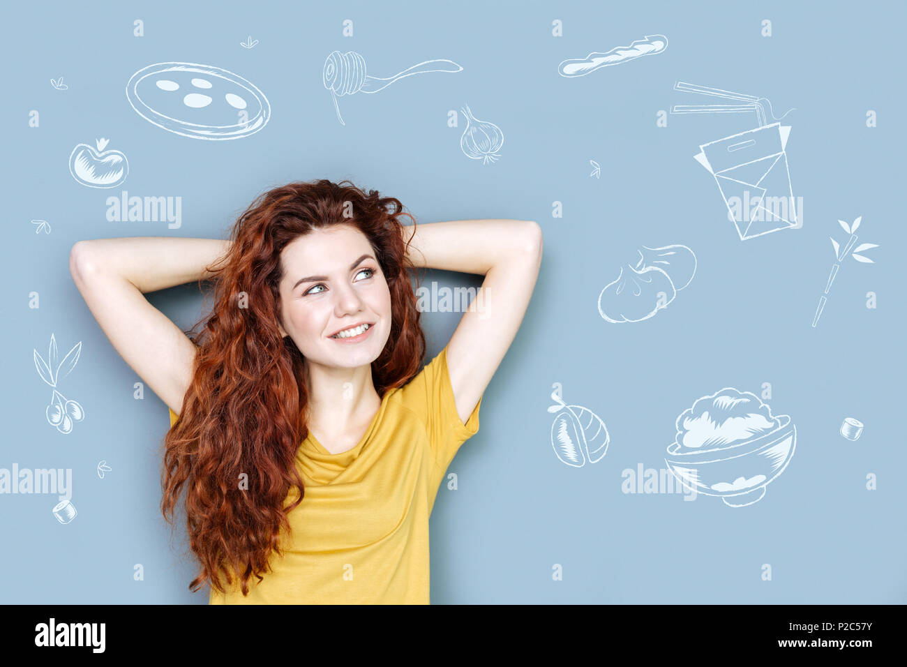 Carino fame studente sorridere mentre pensando di cibo gustoso Foto Stock