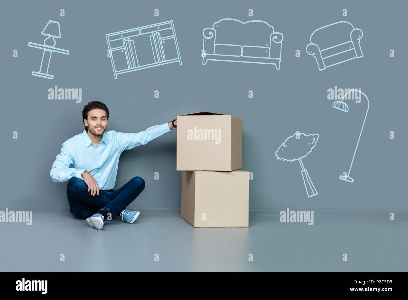 Emotional uomo seduto sul pavimento dopo lo spostamento a una casa vuota Foto Stock