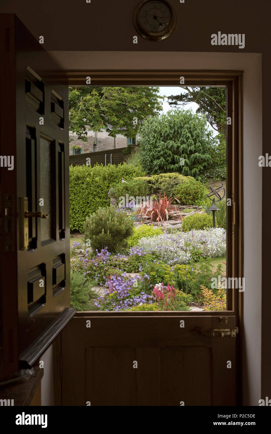 Vista di un paese giardino visto attraverso una stabile della porta in stile Foto Stock