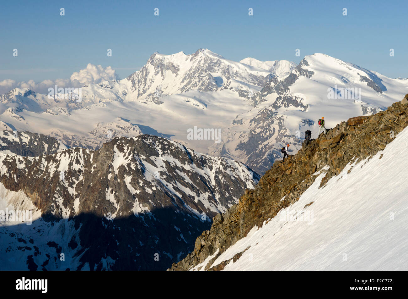 Tre alpinisti sulla cresta sud della Weissmies, in background, da sinistra a destra, il Monte Rosa, Lyskamm e Strahlhorn, Foto Stock