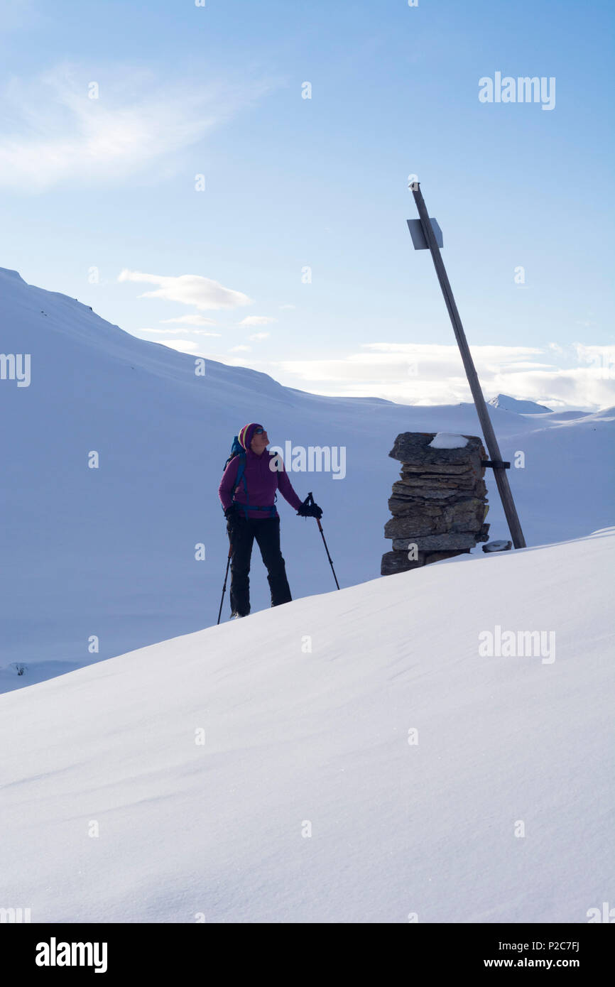 Una femmina di backcountry rider guardando un cartello nella valle innevata denominato Val Camadra, Alpi Lepontine, Canton Ticino, Svizzera Foto Stock