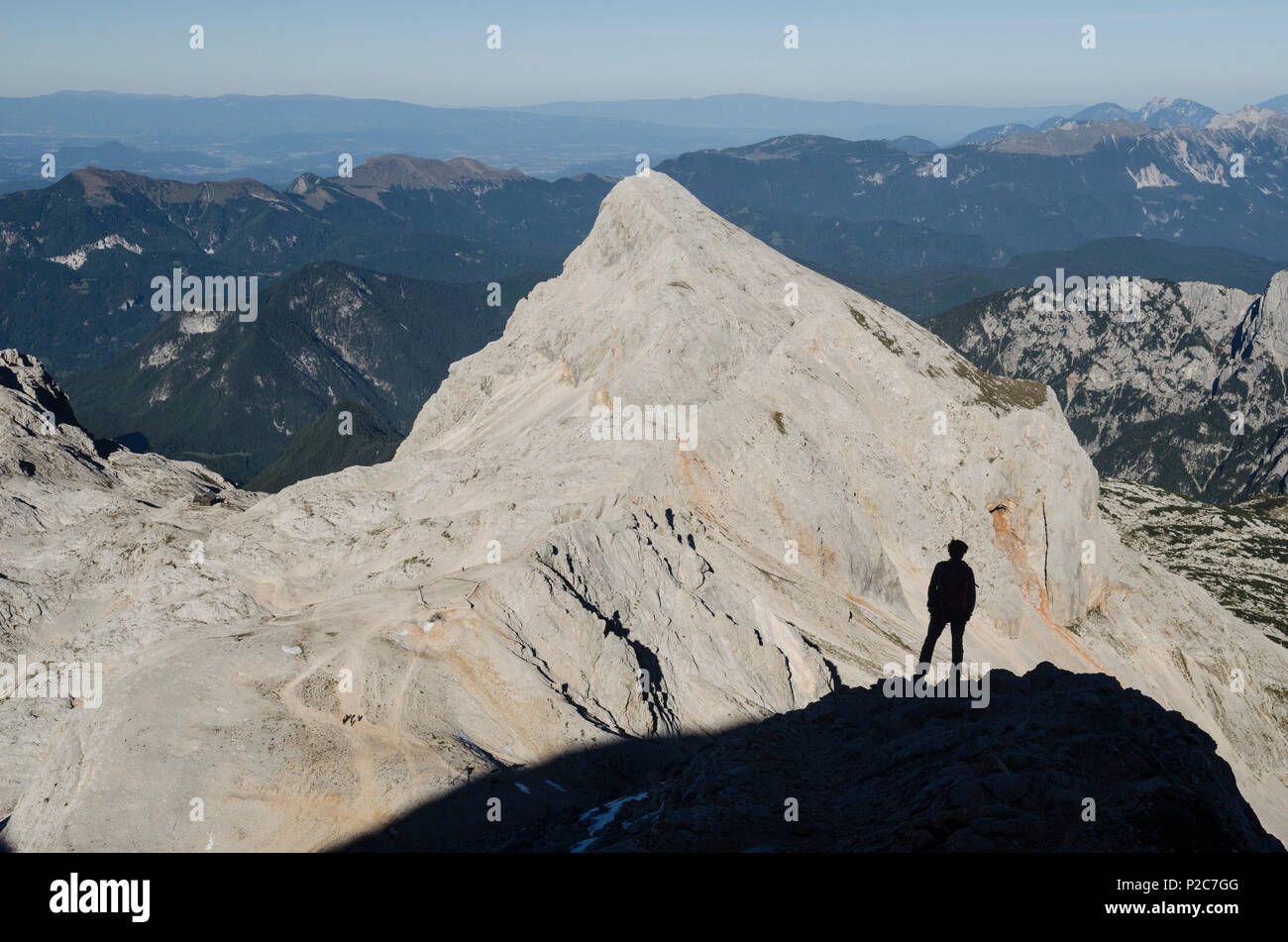 Un escursionista permanente sulla spalla del Triglav, dietro al centro della foto Monte Rjavina, sulle Alpi Giulie, Slovenia Foto Stock