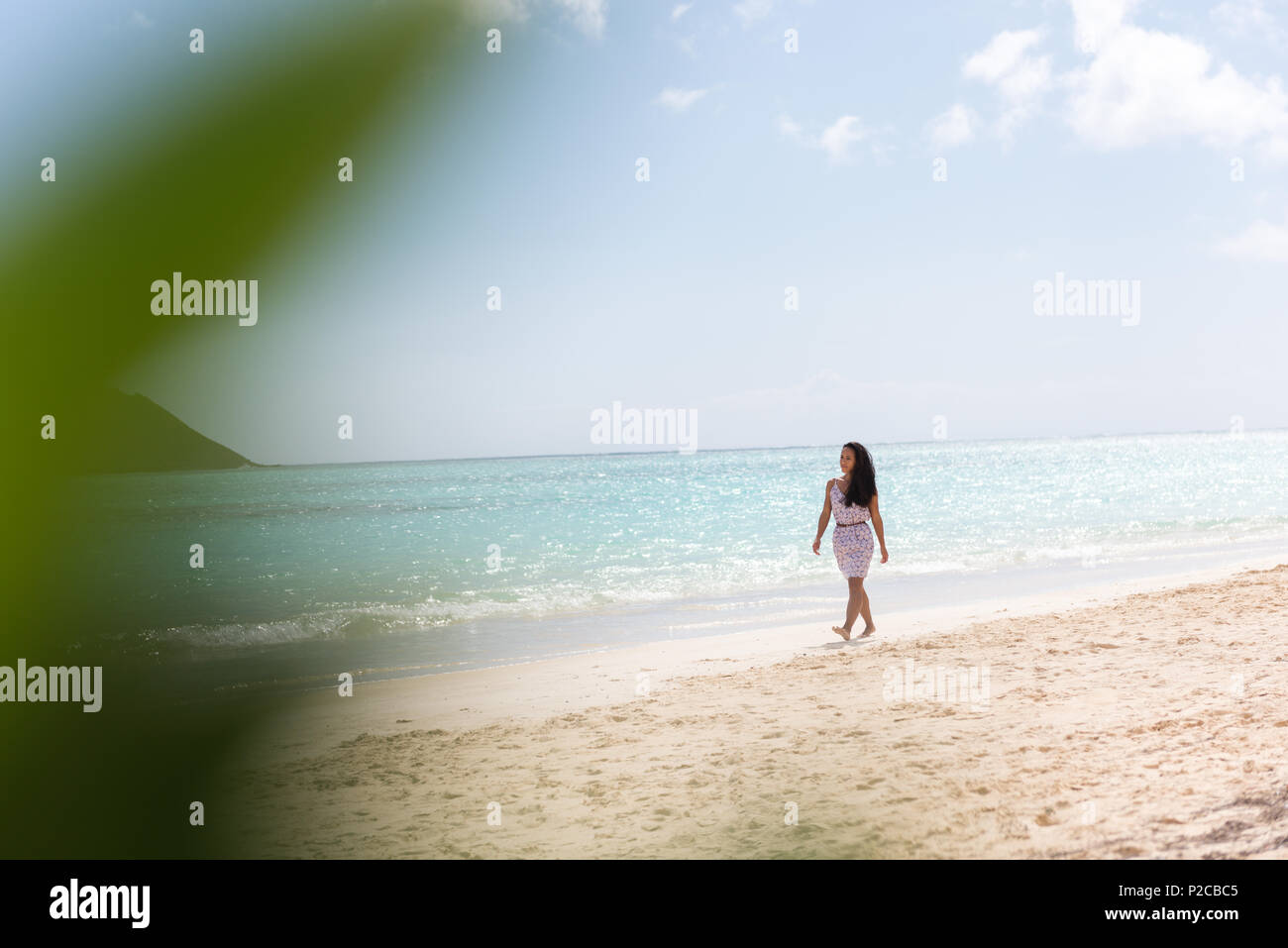 Donna che cammina da sola in spiaggia Foto Stock