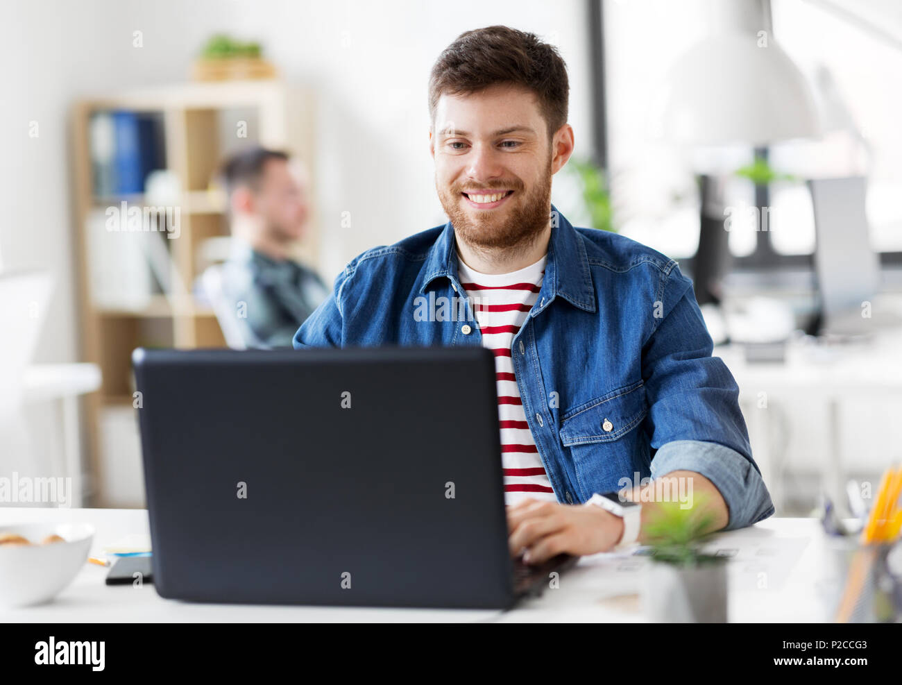 Sorridente uomo creativo con il computer portatile lavorando in ufficio Foto Stock