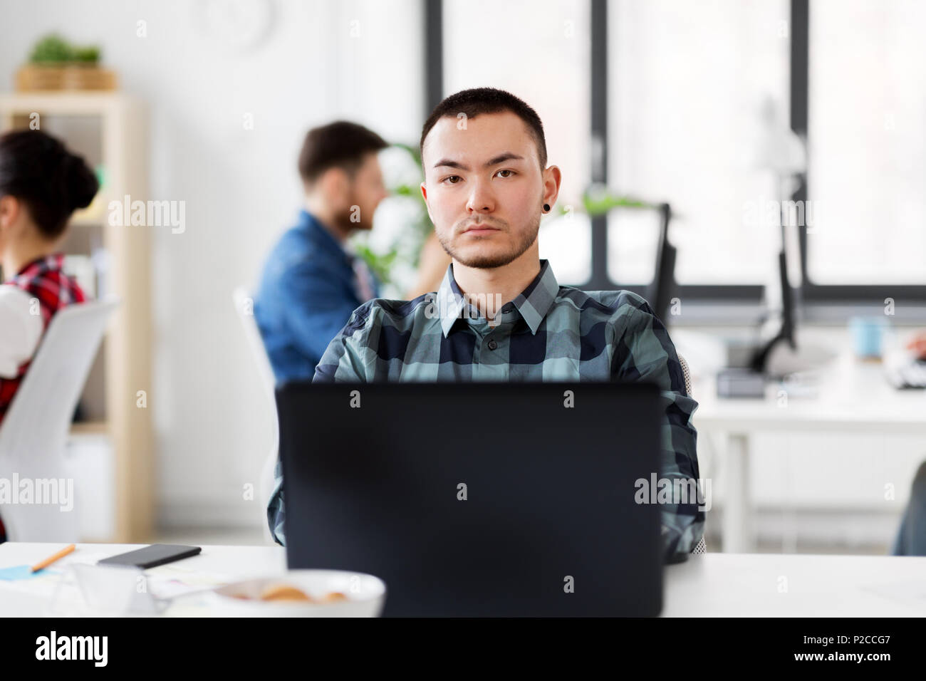 Uomo creativo con il computer portatile lavorando in ufficio Foto Stock