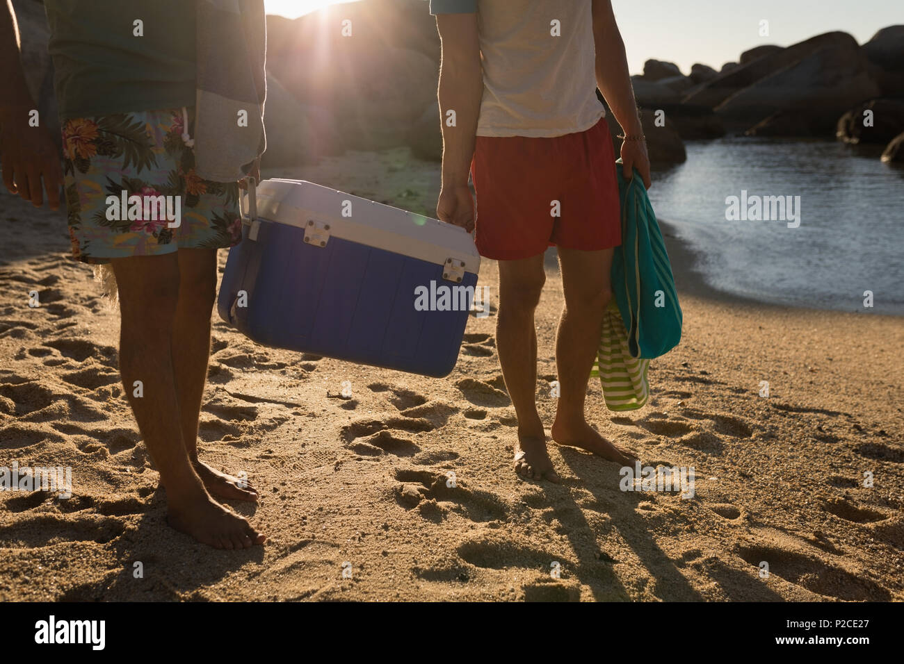 Amici di sesso maschile che trasportano esky in spiaggia Foto Stock