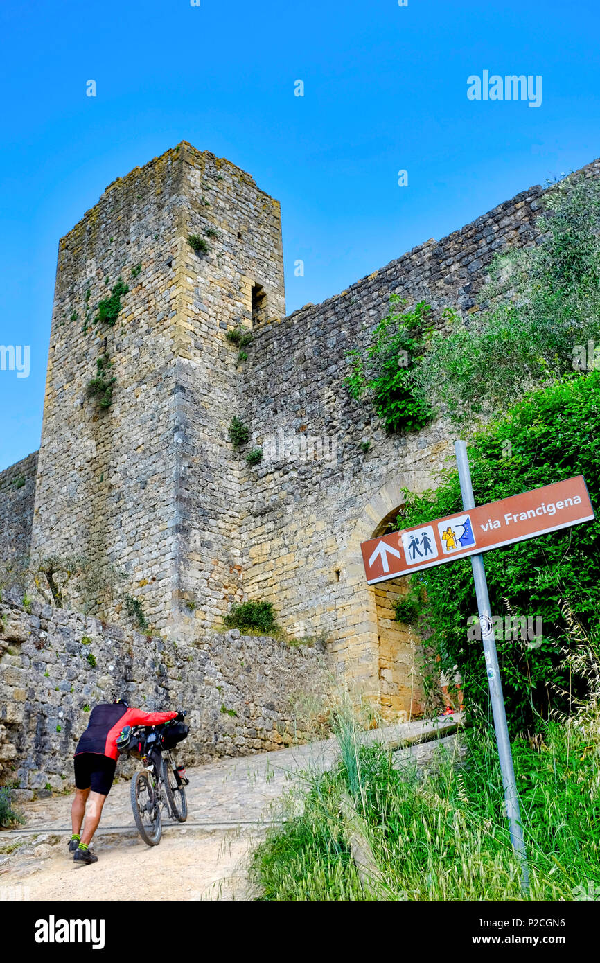 Ciclista sulla Via Francigena entrando in Monteriggioni, Siena, Italia Foto Stock