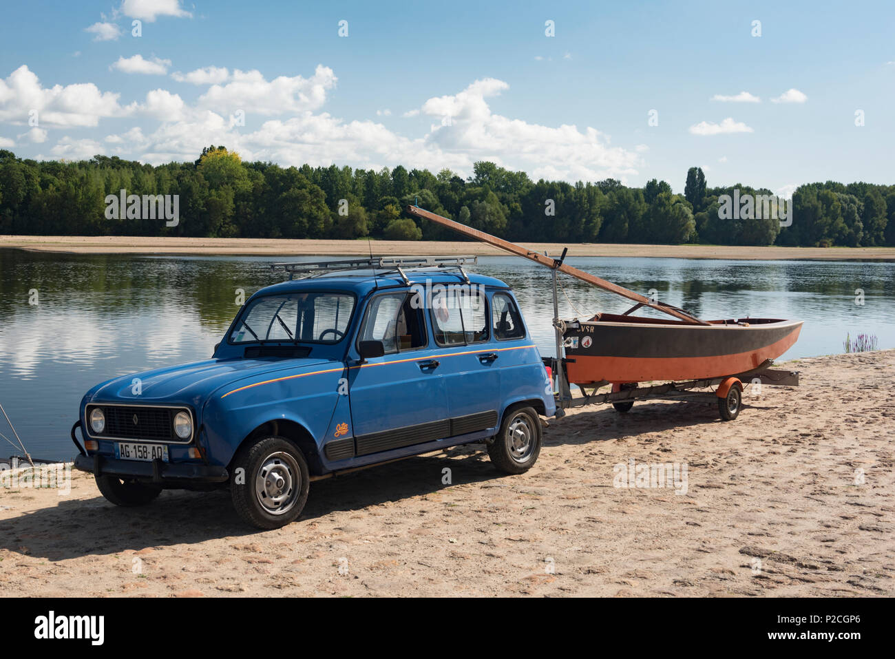Un blue Renault 4 con un rimorchio attaccato portando un piccolo yacht a vela. Foto Stock