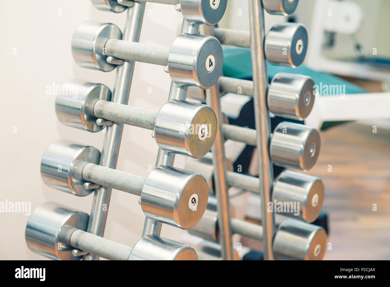 Righe di metallo pesante manubri su supporto in sport palestra, ambulatorio di fisioterapia. La terapia fisica centro. Attrezzature sportive per la formazione. Messa a fuoco selettiva. co Foto Stock