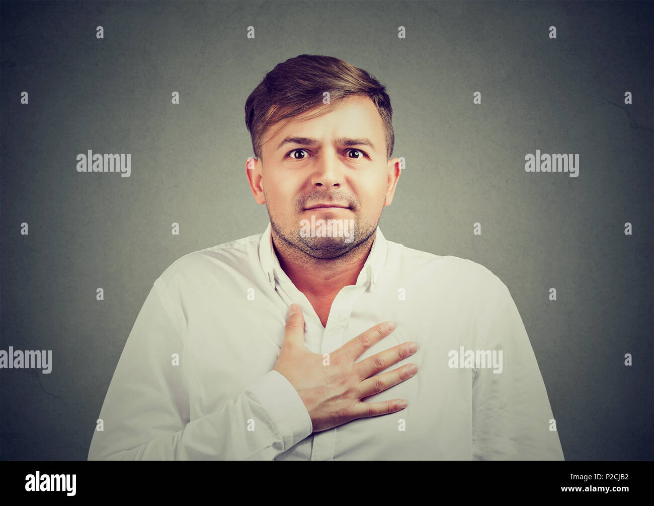 Giovane uomo tenendo la mano sul petto e scusandosi con espressione di rammarico e senso di colpa sulla faccia Foto Stock