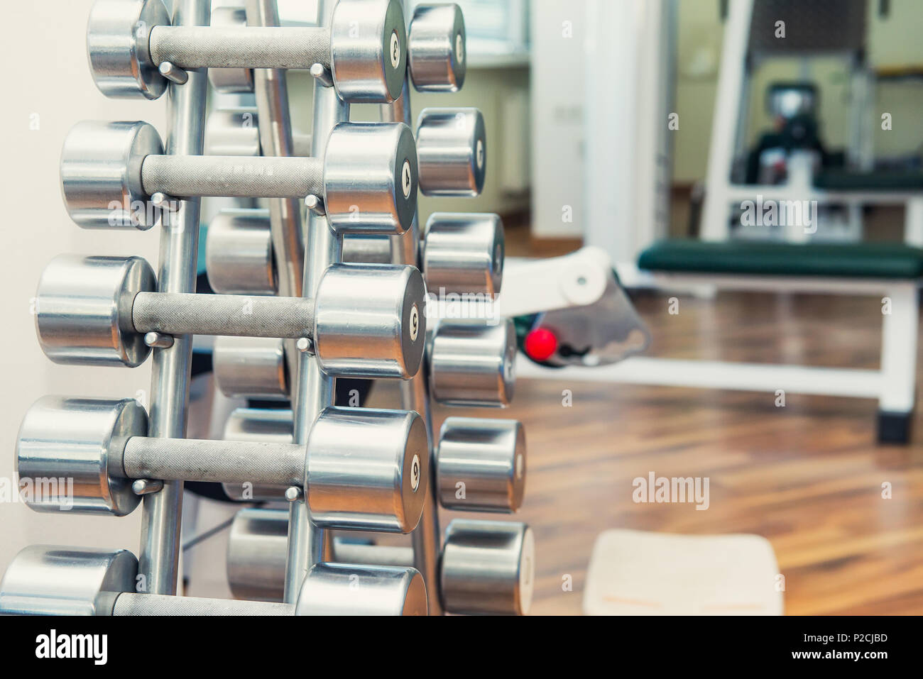 Righe di metallo pesante manubri su supporto in sport palestra, ambulatorio di fisioterapia. La terapia fisica centro. Attrezzature sportive per la formazione. Messa a fuoco selettiva. copia di spazio. Foto Stock