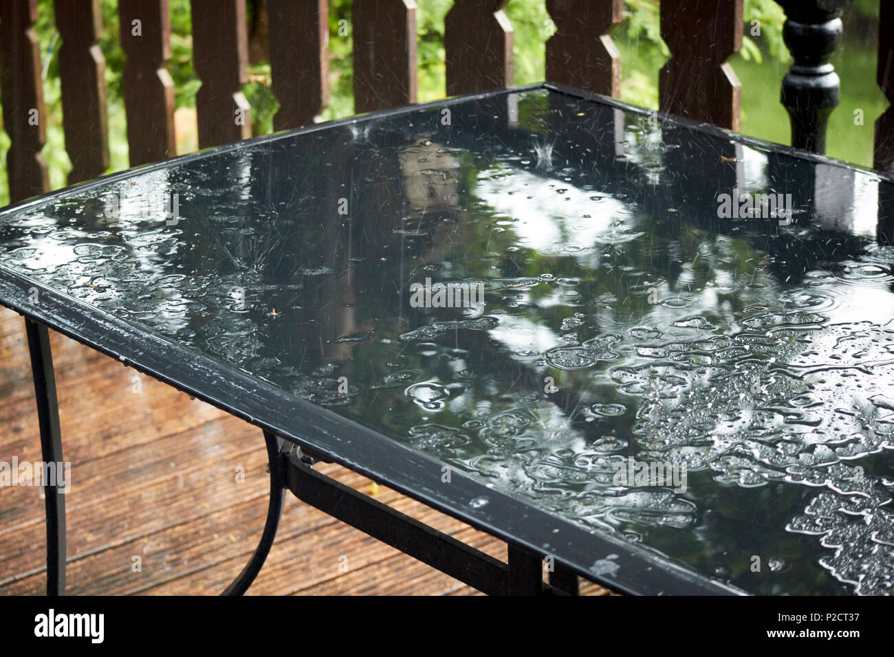 Pioggia rimbalzante su un vetro tavolo da giardino durante bagnato estate meteo nel Regno Unito Foto Stock