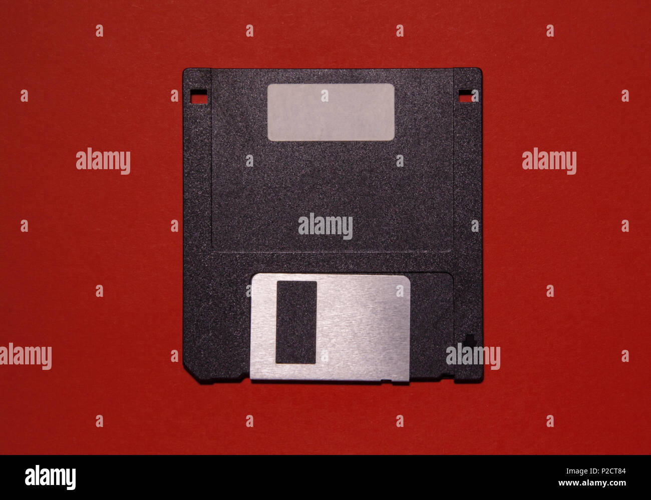 Un obsoleto floppy disk su uno sfondo di colore rosso. È possibile scrivere qualcosa sull'etichetta vuota. Foto Stock