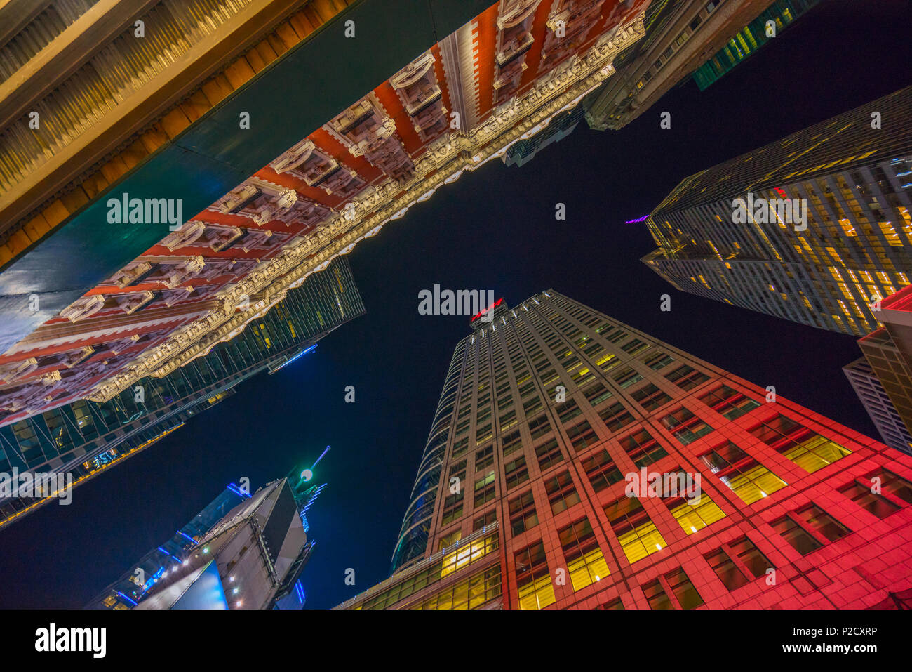Guardando verso il cielo notturno di grattacieli, vicino a Times Square a Manhattan, New York City che illuminato dal luminoso pannelli pubblicitari Foto Stock