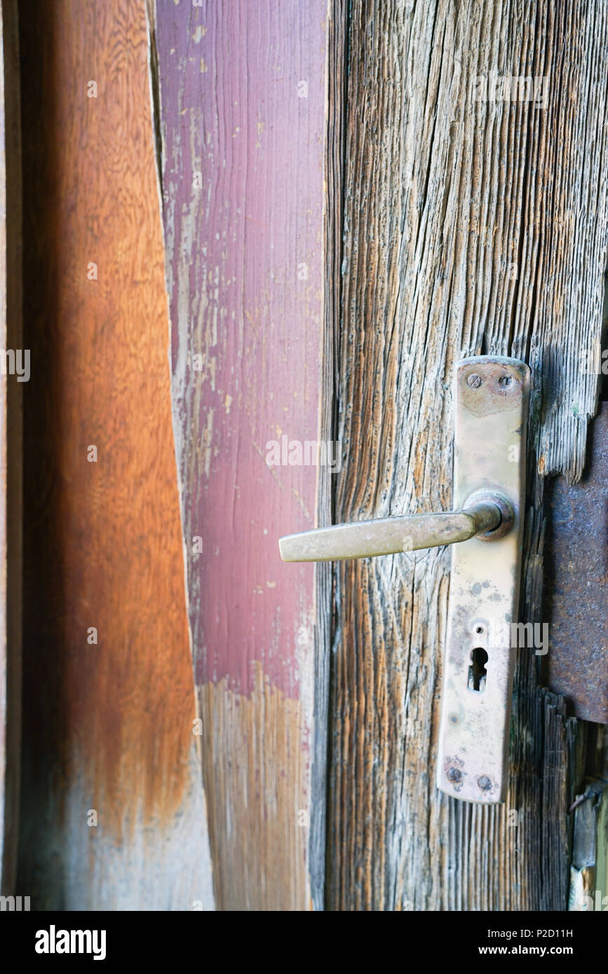 Resti della vecchia porta e la maniglia a leva con weathered di pannelli di legno e alcuni vernice rimanente. Foto Stock