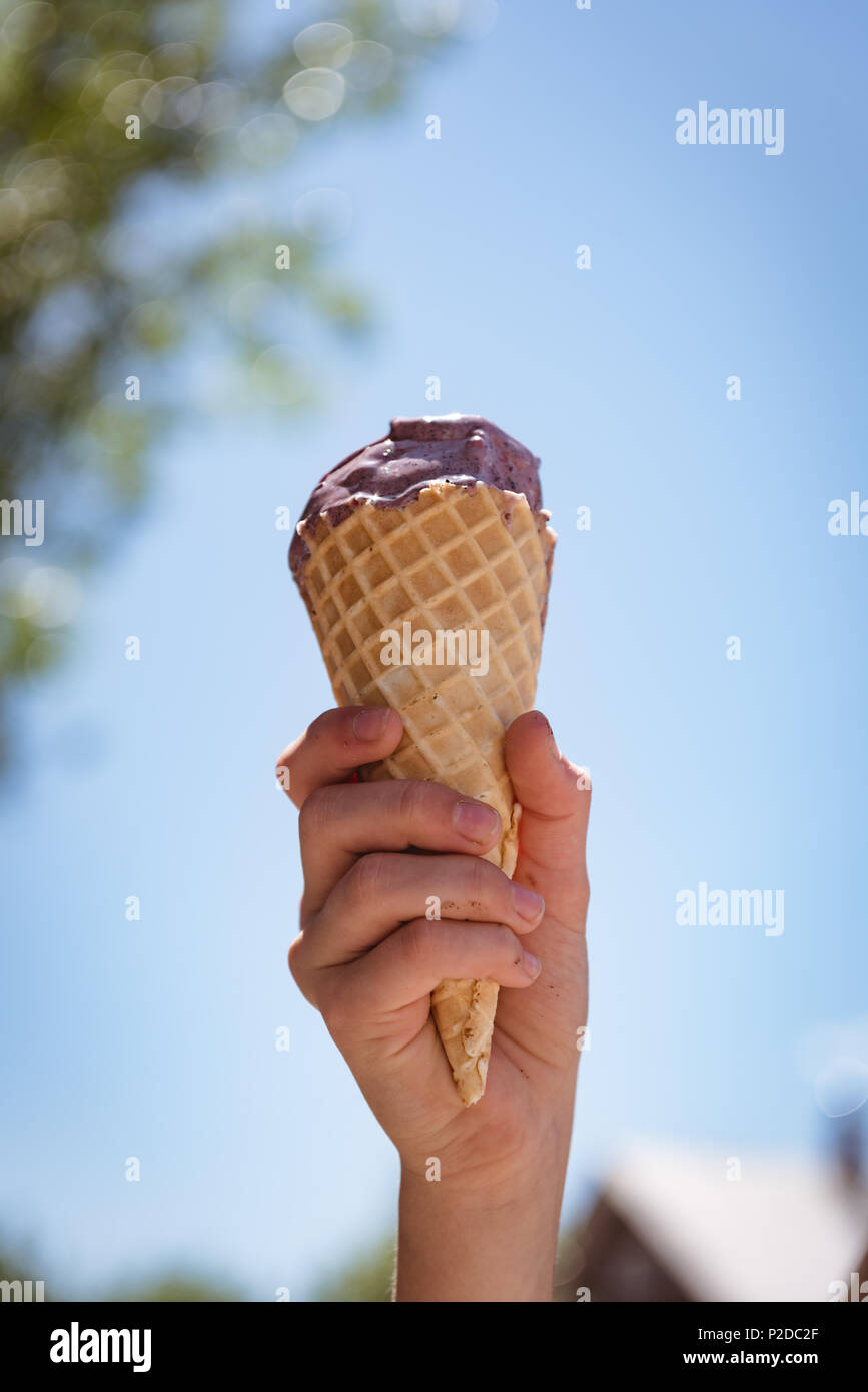 Ragazza mano azienda cono di cialda con gelato in una giornata di sole Foto Stock