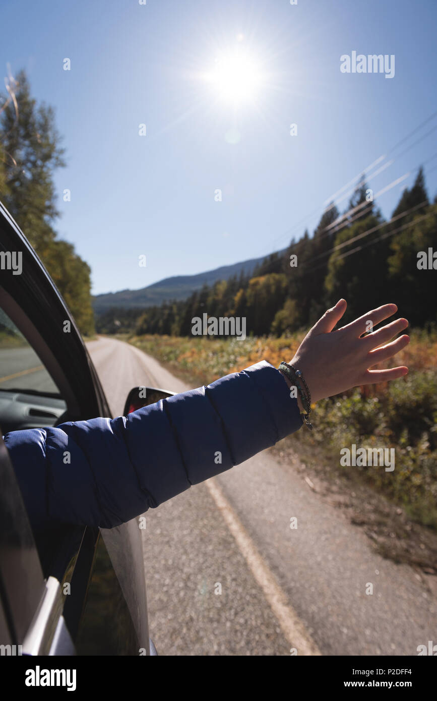 Donna agitando la mano al di fuori della finestra di auto Foto Stock