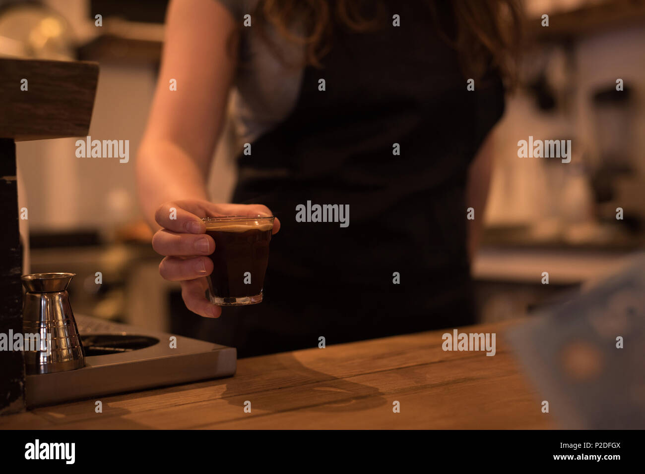La sezione centrale del barista femmina che serve caffè al bancone Foto Stock